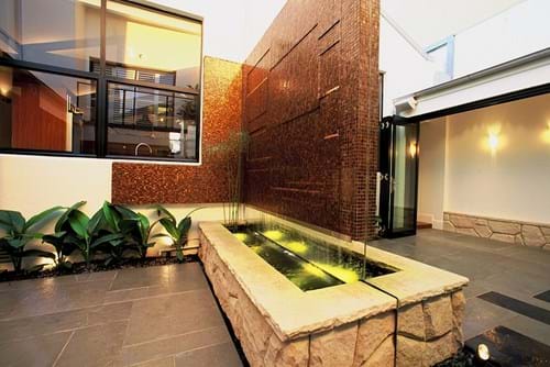 Water feature with tiled spillover wall with mirror surround
