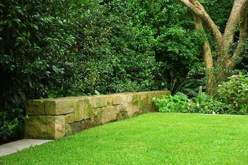 Sandstone block blade wall as a garden feature with mixed planting for green screening