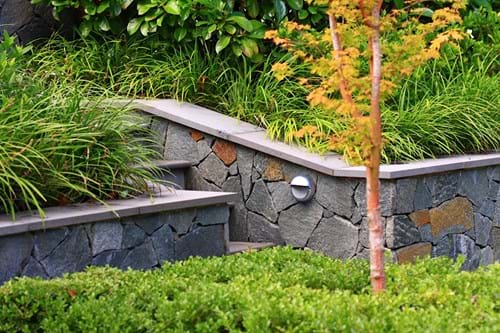 Retaining wall with porphyry stone cladding and bluestone capping